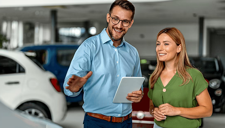 Salesperson guiding a customer through vehicle options at a dealership.