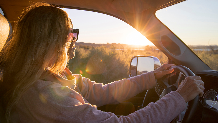 Person driving a vehicle with sunlight shining through the window.