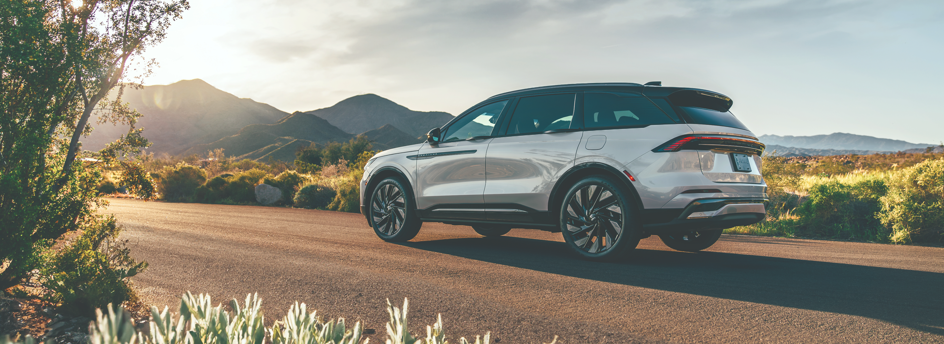 Lincoln SUV parked on a desert highway at sunset.