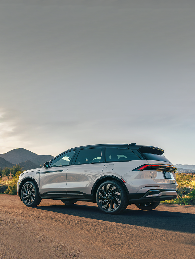 Lincoln SUV parked on a desert highway at sunset.