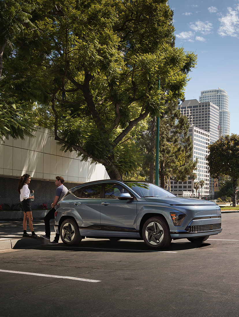 Hyundai SUV parked on a city street with two people talking beside the vehicle.