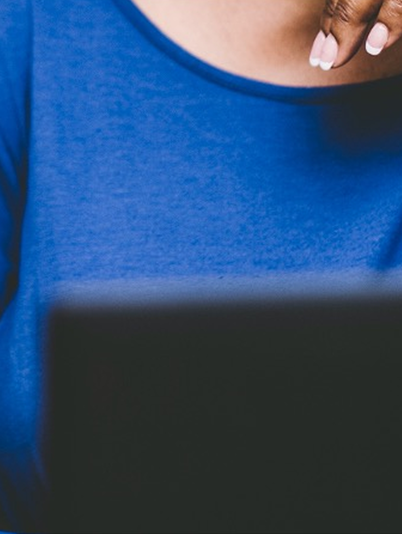 Person using a laptop at a table with a cup nearby.