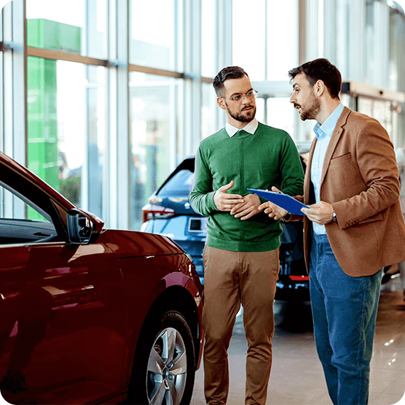 Car salesperson discussing vehicle options with a customer inside a dealership.